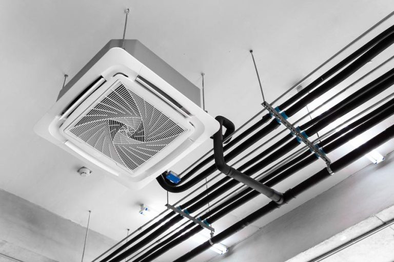 White cassette type air conditioner mounter to the ceiling alongside black tubing