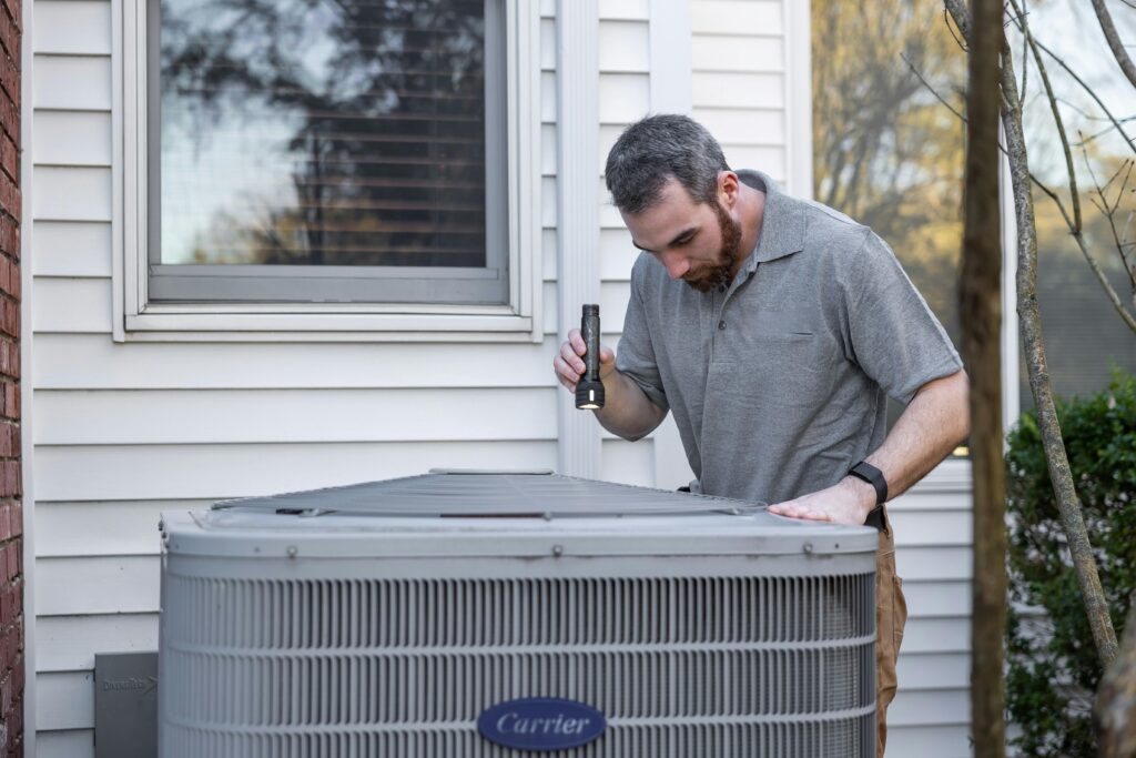 HVAC technician inspecting outdoor air conditioner unit during AC repair service