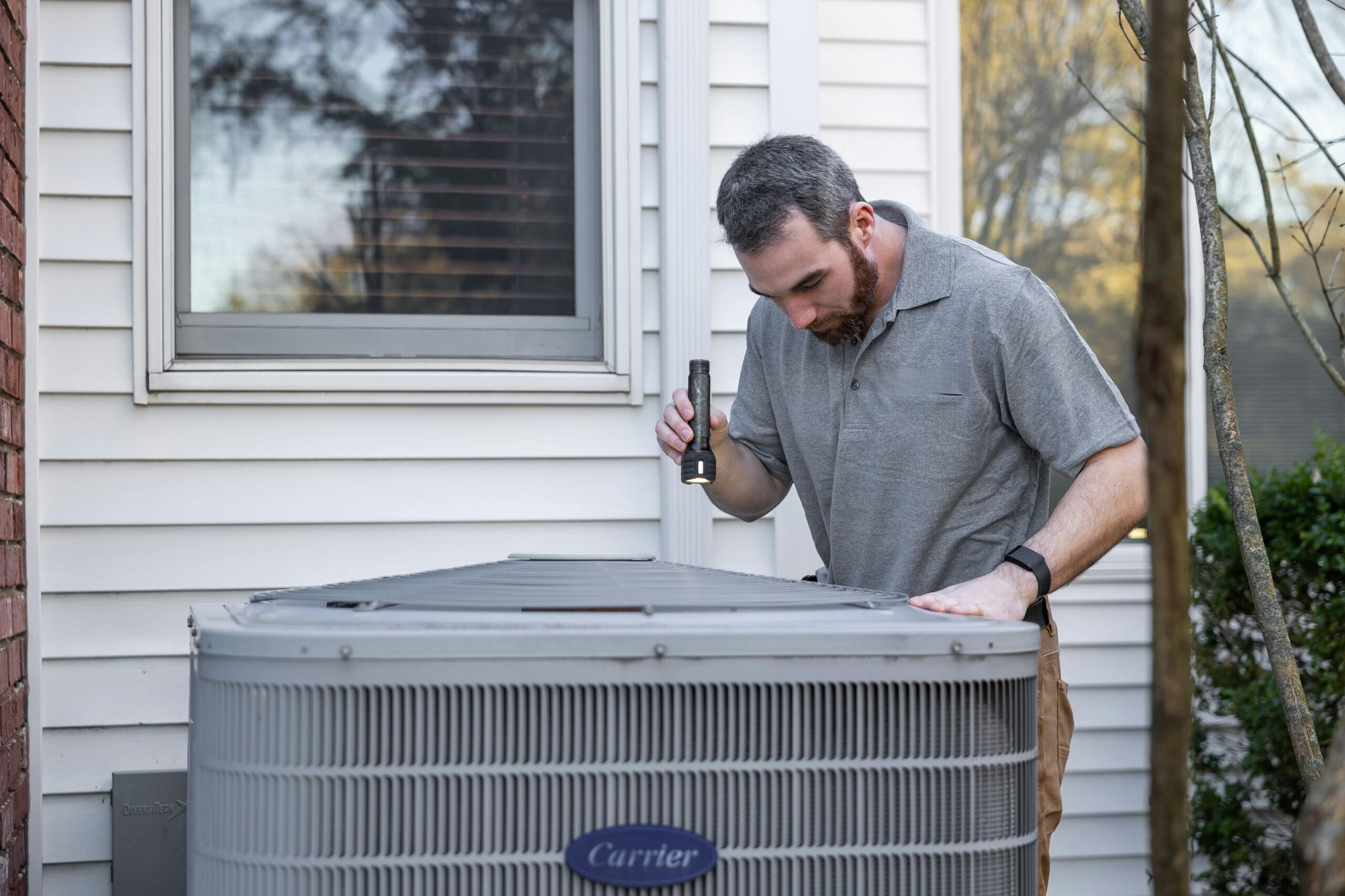 HVAC technician inspecting outdoor air conditioner unit during AC repair service