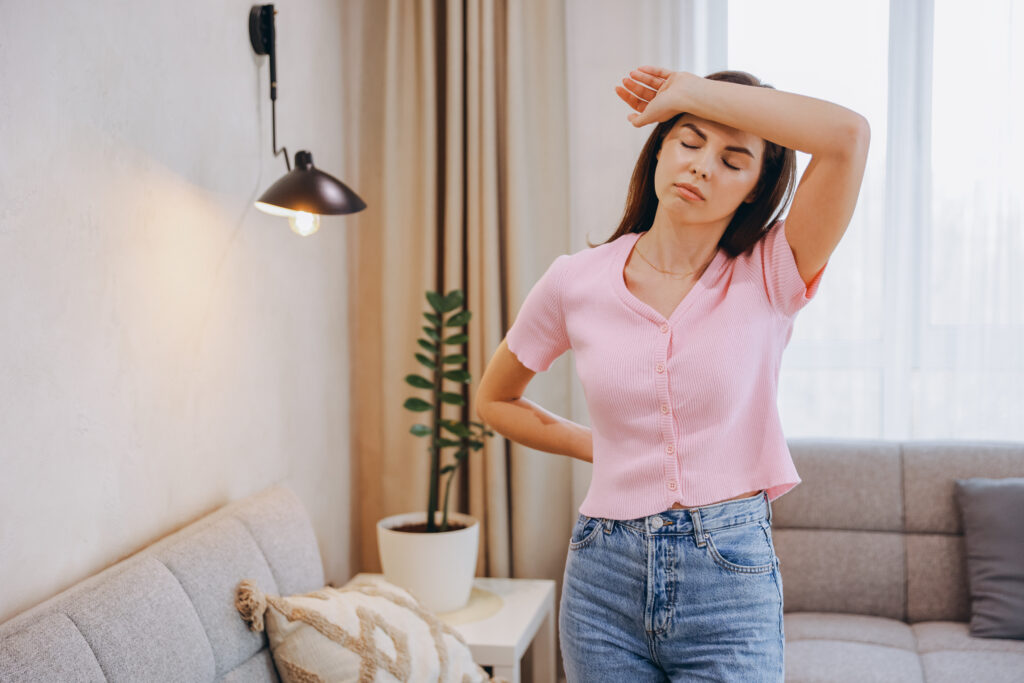 Woman feeling overheated indoors due to uneven home temperatures caused by HVAC airflow issues