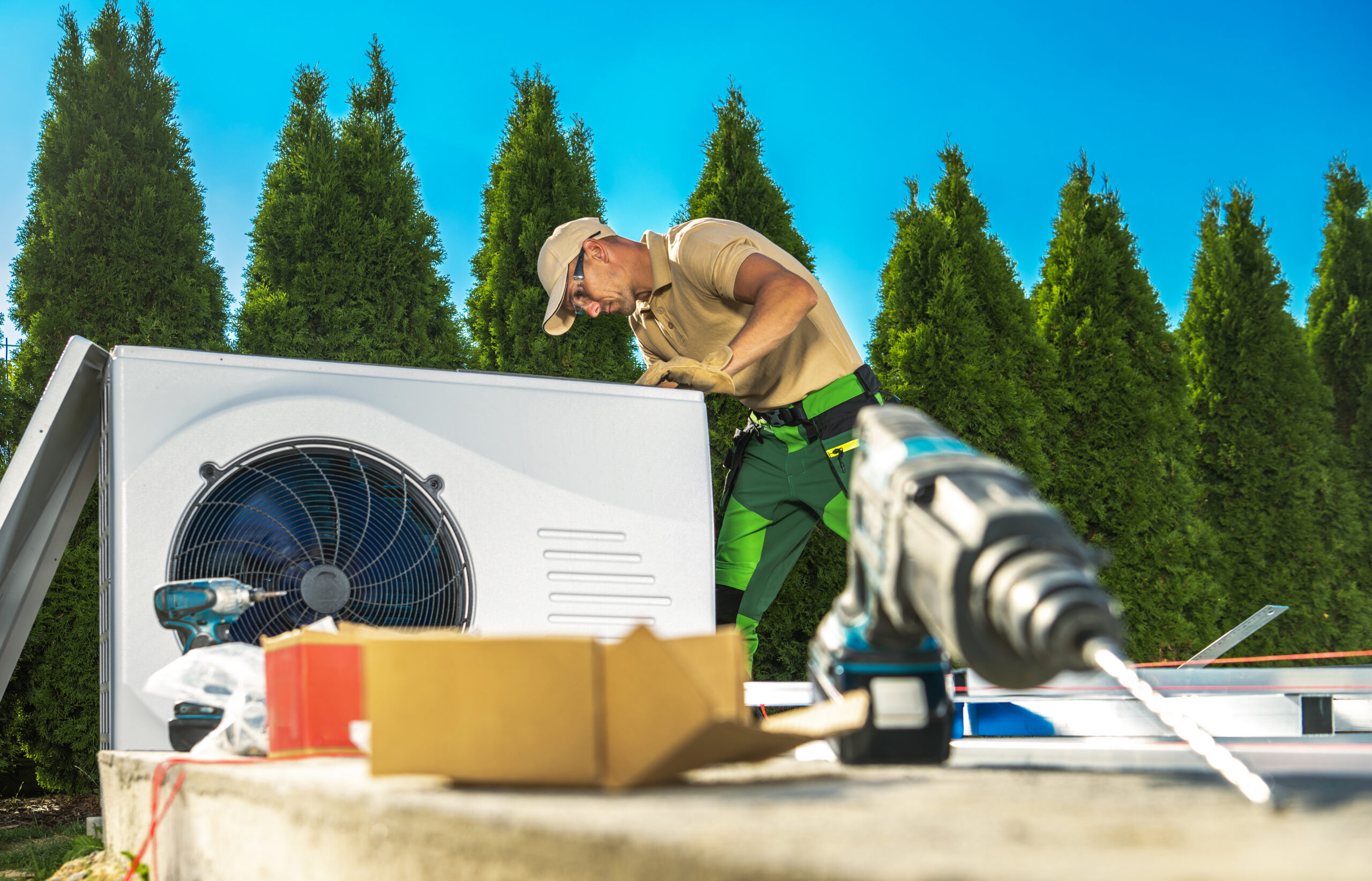 HVAC technician repairing an outdoor air conditioning unit during summer heat to restore cooling and system performance.